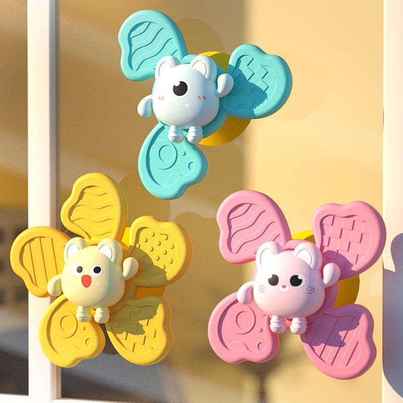 Three suction cup spinning toys stick to the glass window in the sunlight